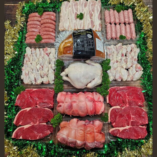 A festive assortment of meats including lamb, pork, ham, chicken, sausages, and bacon, beautifully displayed for a Christmas feast.